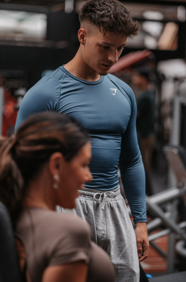 Personal trainer begeleidt een klant bij een lat pulldown oefening